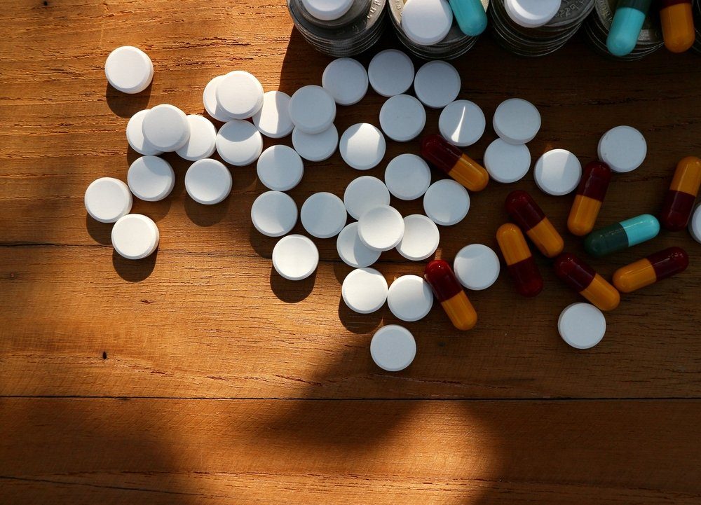 White round pills and capsules with part roll coins money and medicine on wood table in shadow space sunlight